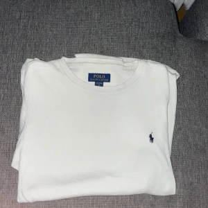 Vit långärmad tröja Polo Ralph Lauren - Vit långärmad tröja från Polo Ralph Lauren med klassisk rund hals och blå broderad logga på bröstet. Tröjan är i ett ribbat bomullsmaterial som känns skönt mot huden. Perfekt för chill dagar eller när du vill ha en clean look. Tunnare material men jätteskönt! Kan diskutera pris vid snabb affär!