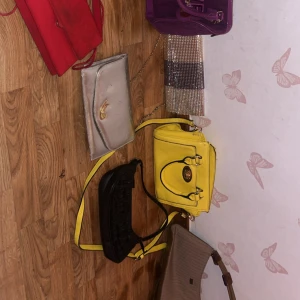 Färgglada handväskor och kuvertväskor - Säljer flera snygga väskor en för 30 alla för 150: en gul handväska med svarta detaljer, en röd kuvertväska, en silverfärgad kuvertväska med kedja, en lila handväska, en glittrig kuvertväska, en svart axelväska med gul rem och en beige axelväska med bruna detaljer. Perfekt för dig som gillar att variera din stil.