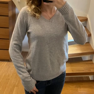 Grå v-ringad stickad tröja från Vila - Mysig grå långärmad stickad tröja från Vila med v-ringning. Tröjan är inte särskilt använd. Det finns lite tecken av användning på ärmarna. Passar perfekt till hösten🤎