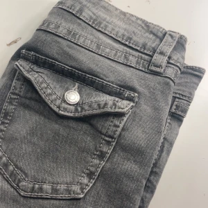 Grå bootcut jeans från Ginatricot - Snygga grå jeans från Ginatricot i bootcut-modell med klassiska fickor och bälteshällor. Jeansen har en cool tvättad look och är tillverkade i mjukt denim-material. Perfekt för dig som gillar retrovibbar och vill ha ett par jeans med lite extra attityd.