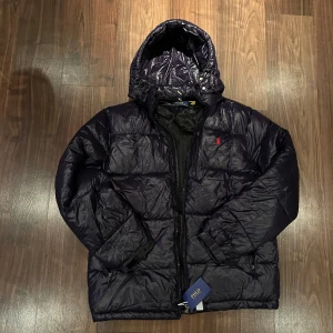 Mörkblå Polo Ralph Lauren jacka  - Snygg mörkblå pufferjacka från Polo Ralph lauren! Tröjan är helt ny men tyvär för stor för mig. Perfekt nu till vintern som kommer och kyliga dagar! Tveka inte av att ställa frågor 