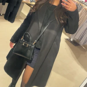 Svart lång kappa - Säljer en svart lång kappa med klassisk krage och rak passform. Kappan är från Vero Moda och är i storlek Xs men passar även Xxs-M. Finns lite tecken av användning på kappan då den har blivit lite nopprig men går bort snabbt med hjälp av en rakhyvel 