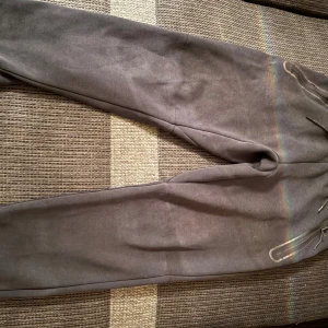 Svarta mjukisbyxor från Nike - Svarta mjukisbyxor från Nike med baggy passform och dragkedjor vid fickorna. Byxorna har snörning i midjan och är tillverkade i mjukt bomullsmaterial. Perfekta för chill eller träning, med Nike-logga på benet.