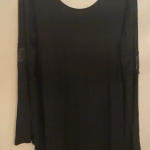 Svart långärmad topp från ONLY - Svart långärmad topp från ONLY med rund hals och snygga spetsdetaljer på ärmarna. Tunn och mjuk i materialet, perfekt för dig som gillar stilrena plagg med en liten twist. Passar dig som vill ha en enkel men ändå lite extra look.