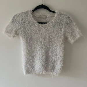 Vit fluffig stickad tröja - Supermysig vit stickad tröja med korta ärmar och fluffig, lurvig yta som ger en unik look. Rund halsringning och loose passform, perfekt för dig som gillar att sticka ut med din stil. Passar dig som vill ha något annorlunda och comfy.