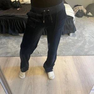 Mörkblåa  mjukisbyxor Juicy Couture XS - Säljer ett par mörkblåa mjukisbyxor från Juicy Couture i storlek XS. Byxorna har bred resår i midjan med snörning, stora fickor fram och bak med guldfärgade knappar. Materialet är mjukt och sammetliknande, perfekt för chill dagar.