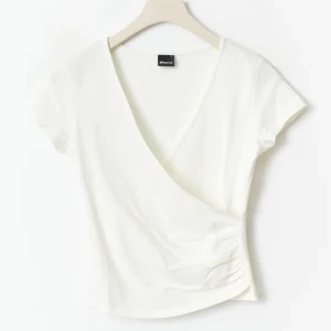 Vit omlottopp med v-ringning - Säljer en fräsch vit omlottopp med djup v-ringning och korta ärmar. Toppen har en snygg, figurnära passform som framhäver midjan. Perfekt för dig som gillar stilrena och enkla plagg med en twist. Helt ny använd 1 gång, strl M men skulle mer säga att den är som en S eller XS