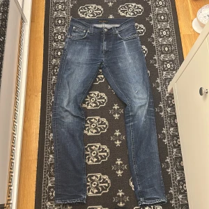 Blå skinny jeans från Nudie Jeans - Snygga blå jeans från Nudie Jeans i modellen skinny med klassisk femficksdesign och coola slitningar. Jeansen har normal passform, med medelblå tvätt och kontrastsömmar. Perfekt för dig som gillar en smal siluett och stilren look. Priset är ej hugget i sten så om om du undrar något är det bara att kontakta mig.