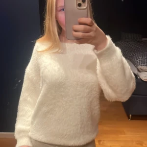 Fluffig vit stickad tröja från Nitted - Supermjuk och fluffig vit stickad tröja från nitted. Tröjan har rund hals, lång ärm och en riktigt cozy känsla. Tröjan har förut haft ett hål i sig men efter som den är så fluffig så har jag sytt igen de hålet och de fluffiga gör att de inte syns alls att jag har sytt.
