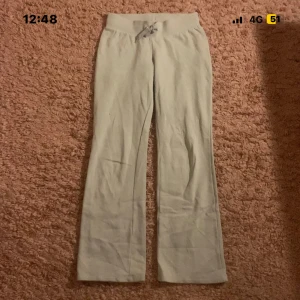 Beige mjukisbyxor med snörning H&M - Snygga beige mjukisbyxor från H&M i storlek 158. De har bootcut-ben och en bred, ribbad midja med snörning framtill. Perfekta för chill dagar och riktigt sköna tack vare det mjuka bomullsmaterialet.