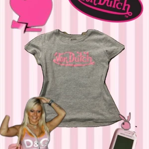 Grå Von Dutch t-shirt med rosa tryck - Grå t-shirt från Von Dutch med ikoniskt rosa logotyptryck på bröstet. Klassisk rund halsringning och korta ärmar. Perfekt för dig som gillar Y2K-stilen och vill sticka ut med en retrovibe.