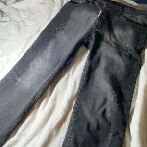 Grå Dsquared2 jeans ICON - Snygga grå jeans från Dsquared2 med ICON-lapp bak och diskreta slitningar framtill. Jeansen har en rak passform, klassiska fem fickor och dragkedja. Perfekta för dig som gillar streetstyle och vill sticka ut med en exklusiv look. Äkta!!