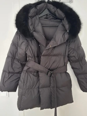 Svart pufferjacka  - Säljer en svart pufferjacka från fur Stockholm, Lilly jacket. Jackan har bälte i midjan för snygg passform och använd några gånger förra vintern! Inga defekter super fin. Kan gå ner vid snabb affär 
