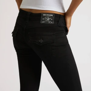 Svarta jeans True Religion - Svarta jeans från True Religion med skinny passform och låg midja. Snygga detaljer som bakfickor med lock och knapp, samt klassisk True Religion patch bak. Perfekta för dig som gillar en tajt siluett och cool streetstil.