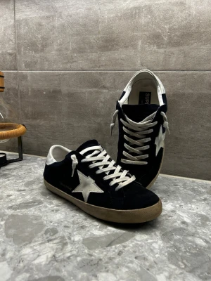 Golden Goose Superstar - Golden Goose skor. Skorna har inte använts mycket och är i bra skick. Säljer pga att de inte kommer till mycket användning✅✅ Strlk 42 | skick 8/10. ⚠️Enda negativa är att dem har blivit lite färgade av mina blåa jeans⚠️