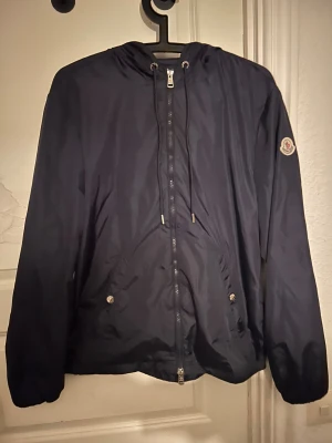 Moncler windbreaker  - Hej säljer nu min moncler windbreaker Sportig och exklusiv Moncler windbreaker i mörkblått. Lätt, vindtät och perfekt för vår.                         , sommar och höst.                                               Endast använd ett fåtal gånger –  i mycket fint skick!  ✔ Storlek: M ✔ Färg: Mörkblå ✔     Skick: Mycket bra.                                                 Superbra jacka för dig som vill ha både stil och funktion! .  tog av tagsen på den rätt så nydligen helt ny!