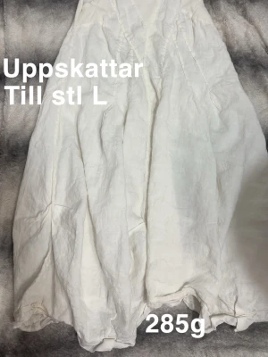 Vit långklänning  - Luftig och stilren vit långklänning med vackra sömdetaljer och lätt rynkad kjol. Perfekt för varma dagar och ger en avslappnad men ändå elegant look.🌸 Fint använt skick. De flesta lappar är borta upplever som storlek L