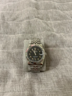 Seiko Mod Arabic Dial 39mm - Säljer min klocka, går tyvärr inte att justera tiden manuellt för någon anledning, men klockan tickar fortfarande och fungerar som normalt (misstänker att den fått damm i sig vid montering).  Annars väldigt nöjd med den, riktigt fin klocka som fångar ögon 👀   • 39mm i diameter • NH35 Seiko automatisk urverk • 3 ATM vattentätt • 316L stainless steel länk (Jubilee). Kan justeras. • Safir glas på både fram och baksida vilket gör att den inte går att repa!  Slänger med en extra dial (tror inte den p