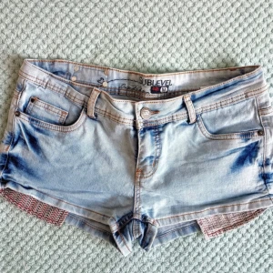 lågmidjade jeansshorts  - Snygga ljusblå jeansshorts från Sublevel med klassisk femficksdesign och coola spetsdetaljer i sidorna. Shortsen har låg midja, bälteshällor och dragkedja med knapp. Perfekta för sommaren och ger en avslappnad vibe.