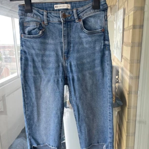  ljusblå jeans Gina Tricot - Säljer ett par Molly Original jeans från Gina Tricot i ljusblå tvätt. Jeansen har hög midja, klassisk femficksdesign och råa, avklippta benslut.