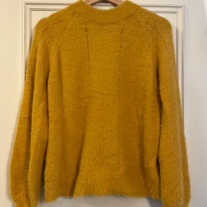 Gul fluffig stickad tröja XS - Supermysig gul stickad tröja från Cubus i storlek XS. Tröjan har en fluffig och mjuk känsla, rund halsringning och långa ärmar. Perfekt för att liva upp höst- och vinterlooken med en poppig färg!