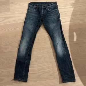 Mörkblå skinny jeans med slitningar - Snygga mörkblå jeans med slim passform och coola slitningar på benen. Klassisk femficksmodell med dragkedja och knapp framtill. Jeansen har en något tvättad look och sitter tight hela vägen ner. Riktigt feta g star jeans.
