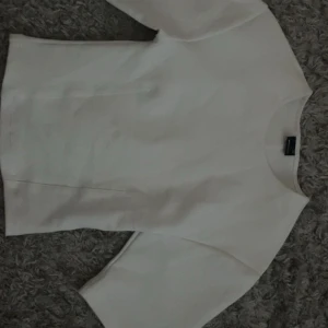 Vit topp med trekvartsärm Gina Tricot - Säljer en stilren vit topp från Gina Tricot i storlek XS. Toppen har trekvartsärmar och en rak, enkel passform. Perfekt att matcha med jeans eller kjol för en clean look. Materialet känns mjukt och bekvämt mot huden.