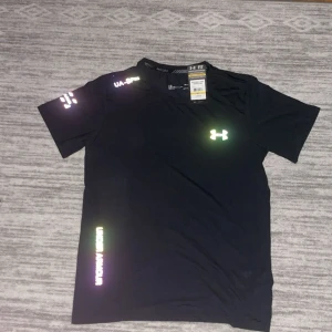Svart lysande Under Armour t-shirt  - Säljer en svart under armour T-shirt som lyser den är i storlek S o är inte använd. Kan gå ner i pris😁