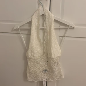Vit/beige gul spetsig halterneck topp S - Supersnygg ljusgul/beige halterneck topp i spets med blommigt spets. Toppen har djup urringning, och är tillverkad i ett lätt, spetsigt material som känns både romantiskt och trendigt. Perfekt för dig som vill sticka ut med en feminin vibe.