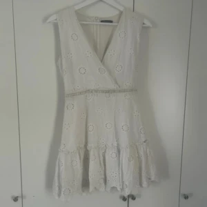 spetsig vit kortklänning  - Superfin vit kortklänning från Trendyol med broderade blommor och volang nertill. Den kommer tyvärr inte till användning längre därför säljer jag den💕