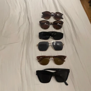 Snygga solglasögonpaket  - Sex par solglasögon i olika former och färger. Ett par Ray-Ban Clubmaster med bruna glas och guldiga detaljer, två par bruna cat-eye och runda bågar, ett par svarta chunky retrobågar med gulddetaljer på sidan, ett par guldiga metallbågar med mörka glas och ett par svarta fyrkantiga bågar. Alla par 350kr 1 par 60kr.