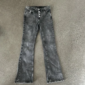 Grå bootcut jeans från H&M, stl 146 - Snygga grå jeans från H&M i bootcut-modell  och fyrasilverfärgade knappar framtill. Perfekta för dig! 