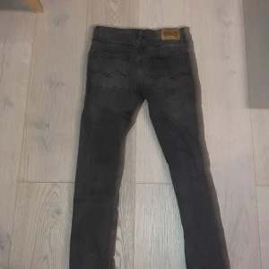 Grå Zirky jeans från Replay, storlek 150 cm - Snygga grå jeans från Replay med klassisk femficksdesign och svarta sömmar på bakfickorna. Jeansen har normal passform och är tillverkade i mjukt denimtyg. Märkespatch bak i midjan och Replay-detaljer vid fickan.