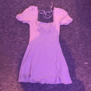 Beige puffärmklänning från NA-KD - Supersöt beige kort klänning från NA-KD med puffärmar och knytning i ryggen. Klänningen har fyrkantig urringning och en lätt utställd kjol. Säljer för 100kr