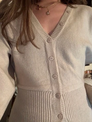 Beige ribbad kofta med knappar - Snygg beige kofta med v-ringning och ribbad midja. Endast testad