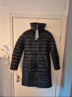 Peak Performance - dunjacka, svart - Svart dunjacka från Peak Performance för Dam. Storlek S Rek pris 4500:-  Outlet pris 2250:-  Jackan är helt oanvänd och i perfekt skick mer prislapp.  Dubbeldragkedja så den går även att öppna nedifrån.  Referenslängder:  Underarm 45cm  Armhåla till höft 66cm  Dragkedja 100cm  Axel till höft 88cm