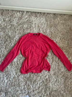 Rosa långärmad tröja - En starkt rosa tröja ifrån Bik Bok. I mjukt och lent tyg, använd ett fåtal gånger. Finns en liten fläck nedanför enda axeln, se bild 2.