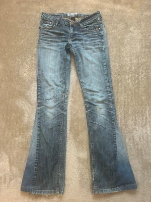 Blå bootcut jeans från G-Star - Snygga blå bootcut jeans från G-Star med slitna detaljer på benen. Jeansen har klassisk femficksdesign och låg midja. De är tyvärr slita mellan bena, då jeansen var köpta så. Passar mig i längd som är 165cm. 