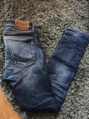 Blå Replay jeans med skinnpatch - Snygga blå jeans från Replay med klassisk femficksdesign och en brun skinnpatch bak i midjan. Jeansen har en lätt tvättad look och raka ben. Perfekta för dig som gillar stilrena och tidlösa jeans.