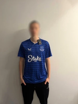 Everton tröja Keane #5  - Säljer en blå Everton matchtröja med Keane och nummer 5 på ryggen. Tröjan har ett vågigt mönster i mörkblått, vit logga samt klubbmärket på bröstet. Perfekt för dig som älskar Everton och vill ha en snygg och billig tröja i bra kvalite. Bara att höra av sig vid frågor. 