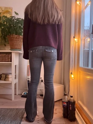 Grå bootcut jeans med fickdetaljer - Säljer ett par gråa bootcut jeans med klassiska fickor bak och fram. Jeansen är insydda i låren och nedersta sömmen är borttagen. Så de avslutas med en rå kant. 
