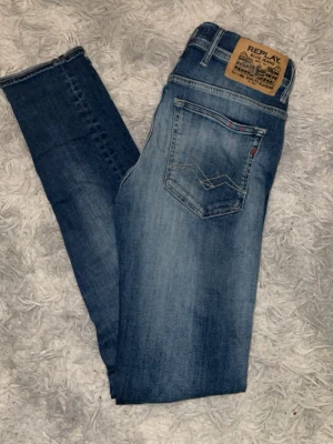 Blå Replay jeans med slitningar - Snygga blå jeans från Replay med slitna detaljer framtill och klassisk femficksdesign. Jeansen har en normal passform och är tillverkade i mjukt denimtyg. Perfekta för en avslappnad och trendig look.