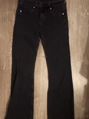 Svarta bootcut jeans från h&m - Snygga svarta bootcut jeans från Divided by H&M. Klassisk femficksmodell med normal passform och utsvängda ben. Jeansen är tillverkade i bomull med en mjuk känsla och har diskreta sömmar. Perfekta för en trendig och avslappnad stil.