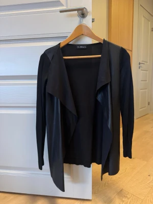 Svart cardigan jacka från Zara - Stilren svart cardigan jacka från Zara med lång ärm och öppen framtill. I läder på framsidan.