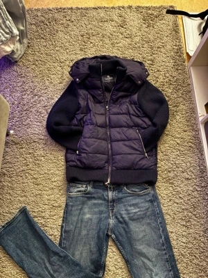 Mörkblå pufferjacka från Vonroe XS - Säljer en mörkblå pufferjacka från Vonroe i storlek XS. Jackan har stickade ärmar och sidor, quiltad front och rygg, samt en stor huva. Dragkedja framtill och två fickor med dragkedja. Perfekt för kyliga dagar och riktigt snygg till jeans.