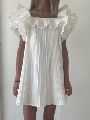 Vit plisserad kortklänning med volang -  Sjukt eftertraktad och populär klänning från Zara 💓Så så fin att ha på studenten!! 💓 kontakta vid frågor annars är det bara att klicka på köp💓💓