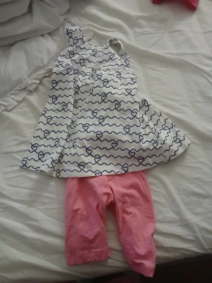 Lupilu set med hjärtmönster och leggings - Sött set från Lupilu med vit ärmlös body med blått hjärtmönster och vågiga linjer, samt rosa leggings. Perfekt för dig som gillar lekfulla och bekväma plagg. Materialet känns mjukt och skönt mot huden.