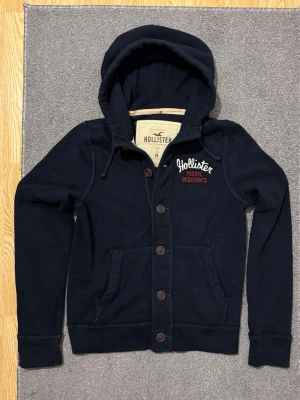 Vintage Hollister Cardigan Med Knappar - Säljer denna otroliga sällsynta och feta Hollister cardigan med knappar | Mycket bra skick | Längd ≈ 65cm, Bredd armhåla - armhåla ≈52cm | Modell 175, 68 kg