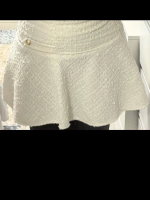 Vit kortkjol från H&M med gulddetalj - Elegant vid kjol med guld detaljer. Perfekt att styla med en enkel topp eller stickad tröja.