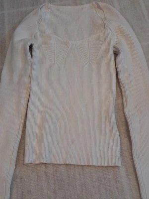 Vit ribbad tröja från SHEIN  - Säljer en vit ribbad långärmad tröja från SHEIN i storlek XS. Tröjan har en snygg, figurnära passform och ett subtilt mönster vid bröstet. Perfekt till både jeans och kjol för en clean look. !!endast swish +frakt!!